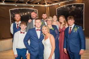 Wedding party group photo with members wearing navy suits and burgundy dresses.