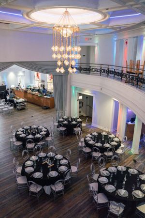 An elegant wedding venue with crystal chandelier and round tables set for reception.