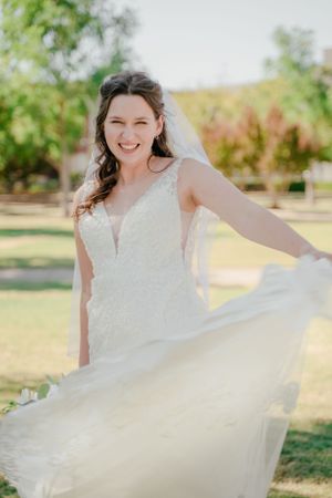 A flowing white wedding dress twirling in a sunny outdoor garden setting.