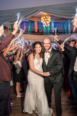 Wedding couple surrounded by guests holding sparklers during reception celebration.
