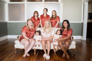 A group photo showing bridesmaids in matching coral robes seated on a white sofa.