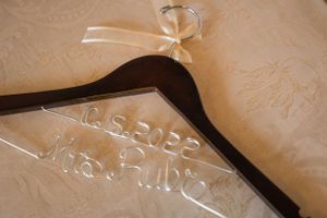 A wooden wedding hanger with 'Mrs. Ruby' engraved on it against a textured background.