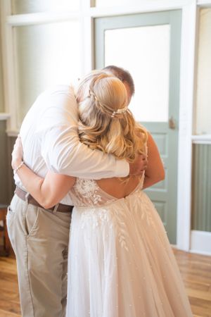 An emotional embrace captured in soft natural light during a wedding ceremony.