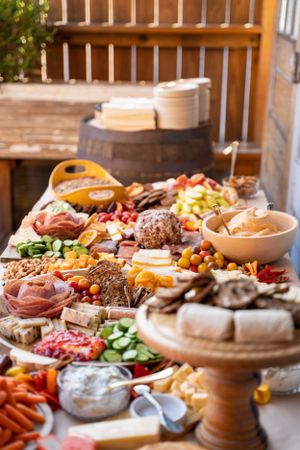 An elaborate charcuterie board display with meats, cheeses, fruits and appetizers on wooden surfaces.