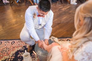 Traditional foot washing ceremony performed during a wedding on an ornate rug.