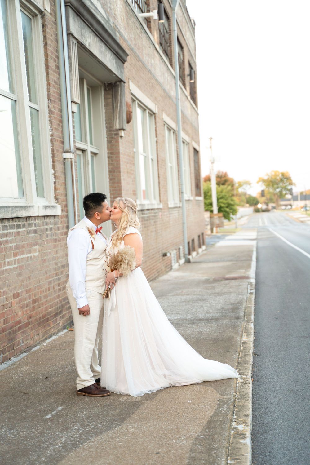 Newlyweds share a moment outside a brick building on their wedding day.