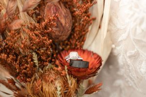 Wedding ring displayed in dried autumn flowers and decorative arrangement.