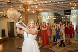Wedding bouquet toss moment with bride and guests in an indoor venue.