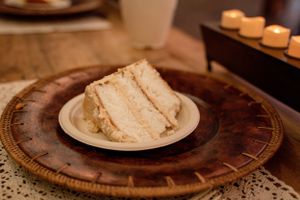Slice of white wedding cake on decorative plate.