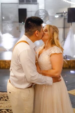 Wedding couple shares romantic dance moment under indoor lighting.