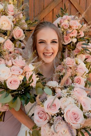 Beautiful wedding bouquet with pink roses and greenery against rustic barn door.