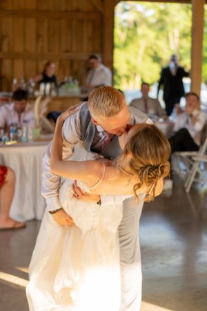 A romantic dance moment captured in a rustic barn setting with golden sunlight.