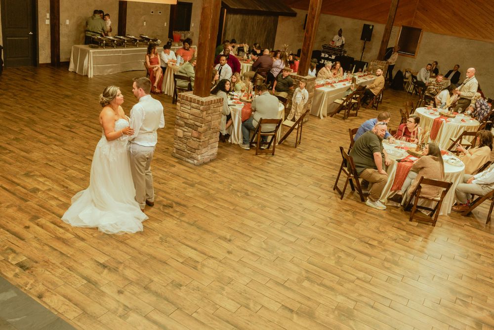 Wedding reception venue with wooden floors and stone accent walls during first dance.
