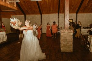 Wedding celebration in rustic venue with wood ceiling beams and dance floor.