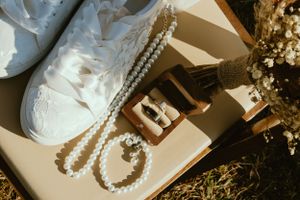 Wedding accessories including pearls, white shoes, and decorative elements in a styled flat lay.
