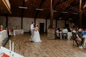 First dance in a rustic wooden venue with string lights and seated guests.