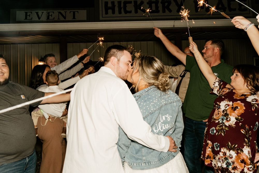 Wedding party dancing and celebrating with raised arms in a rustic indoor venue.