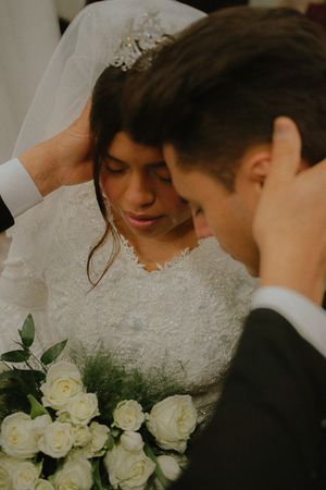 A tender moment between newlyweds with white roses in the foreground.