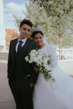 A wedding portrait outdoors with white floral bouquet and elegant attire.