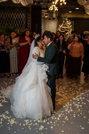 A romantic first dance surrounded by guests and scattered petals on the dance floor.