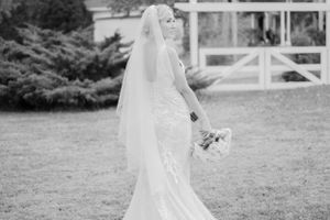 Black and white portrait of a bride in a flowing veil holding a bouquet.