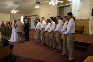 Wedding ceremony in progress with groomsmen lined up in khaki pants and white shirts.