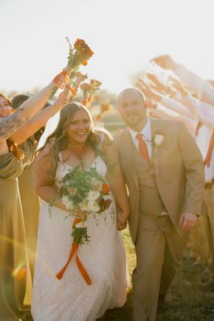 Joyful wedding recessional with guests raising hands in celebration during golden hour.