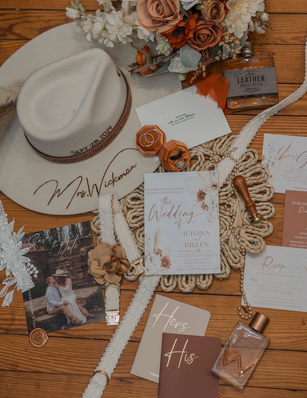 Wedding stationery flatlay with rose gold details, flowers, and invitations on wooden surface.