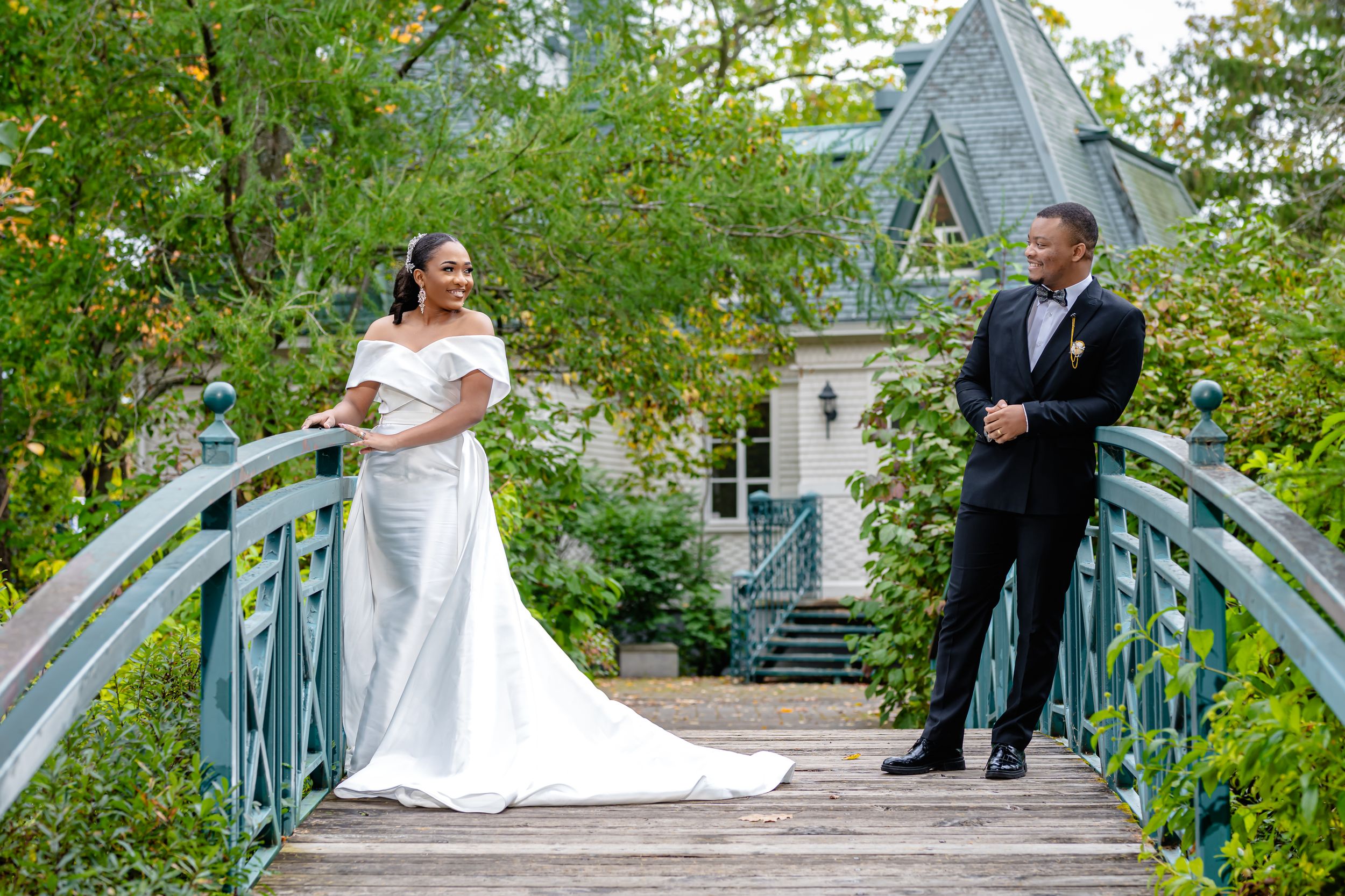 "Couple de mariés sur un pont romantique entouré de verdure, capturé par Payo Studio lors d'un mariage élégant en extérieur."