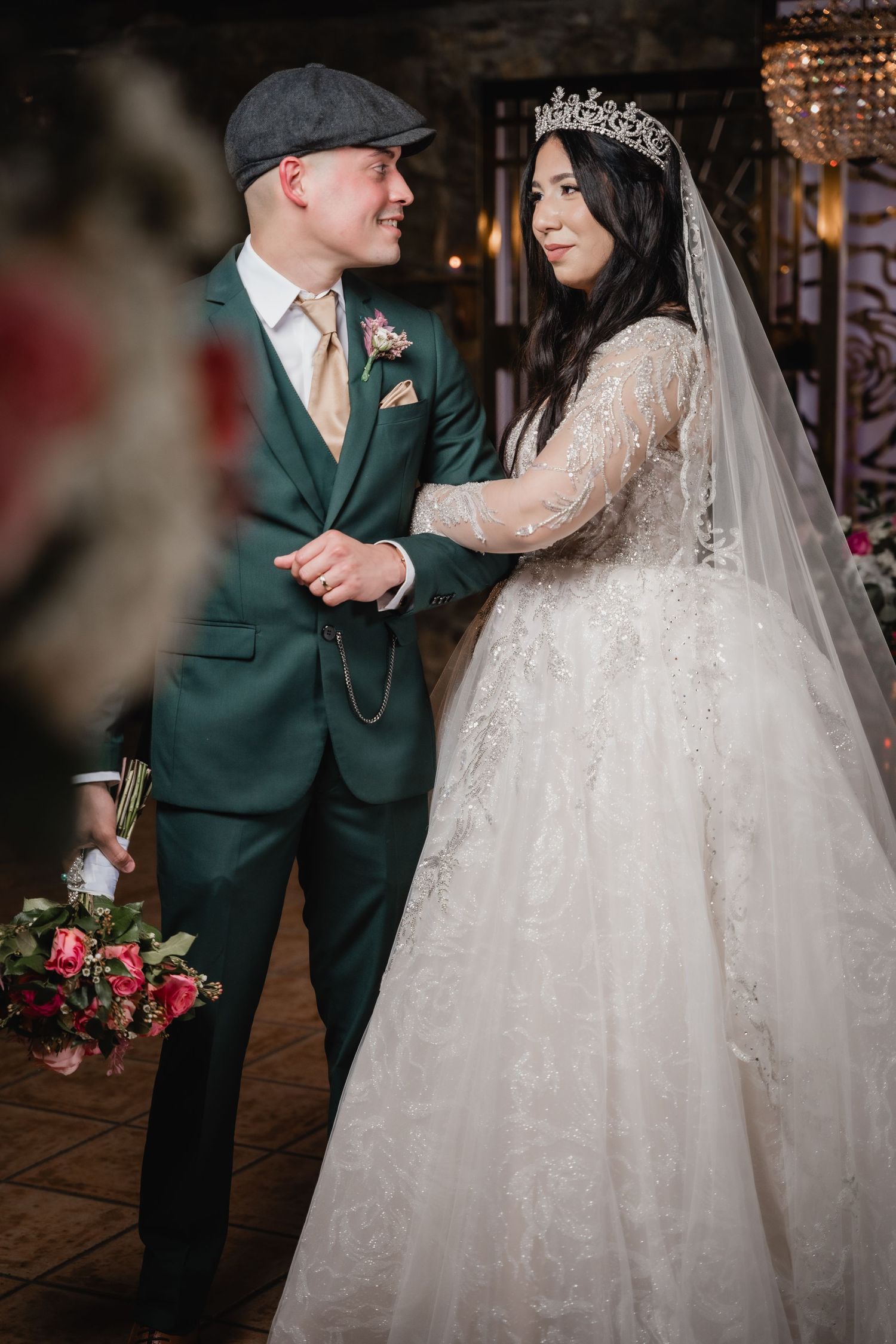 Romantic wedding scene featuring ornate bridal gown and green formal suit.
