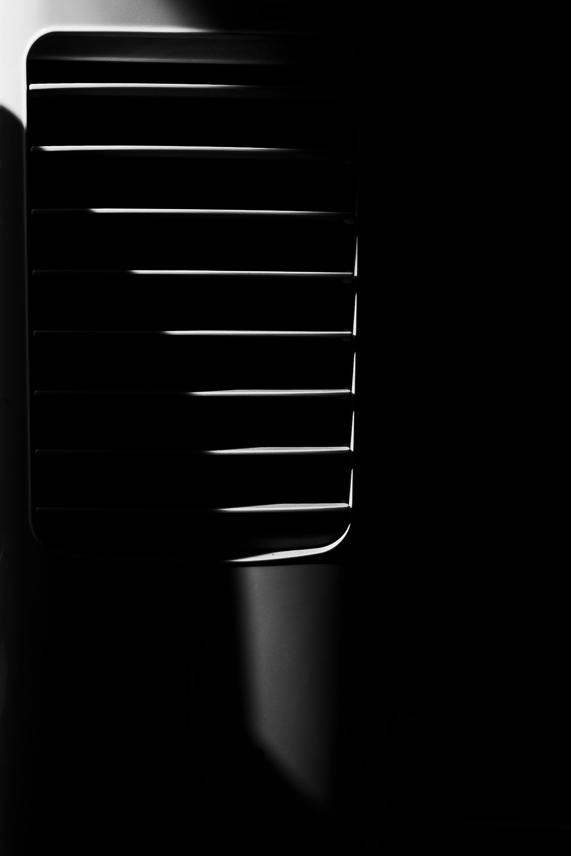 Abstract black and white photograph of ventilation grilles creating geometric patterns.