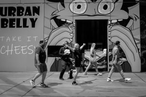 Street dancers performing in front of urban art mural captured in black and white.