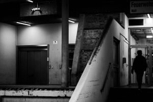 Dark industrial hallway with doors and angular architecture in black and white.