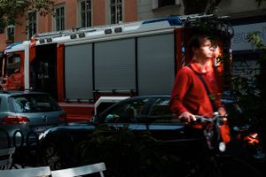 Person in red passing by a fire truck on an urban street.