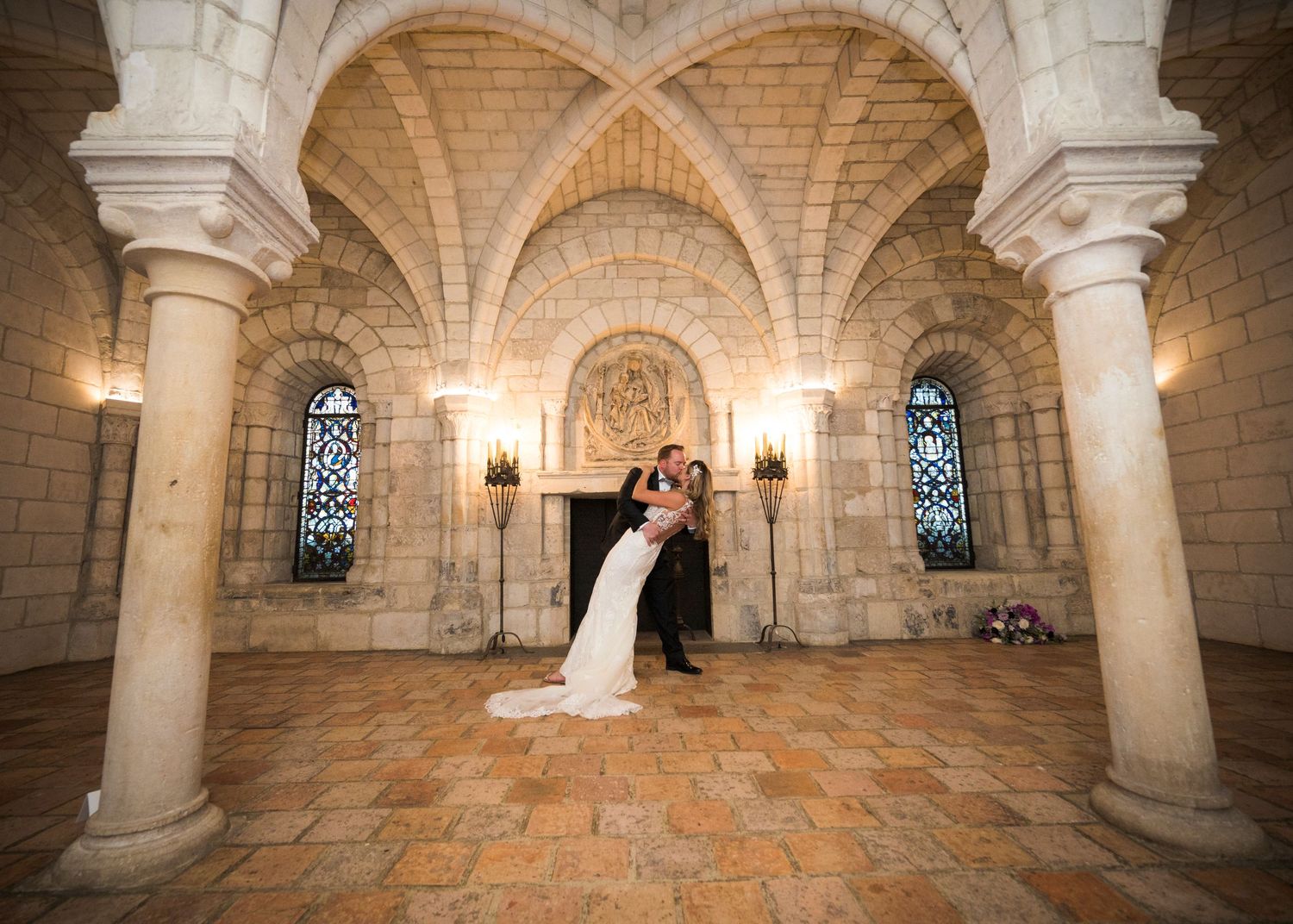 A romantic wedding couple embraces under the Gothic stone arches and vaulted ceilings of an elegant cathedral.