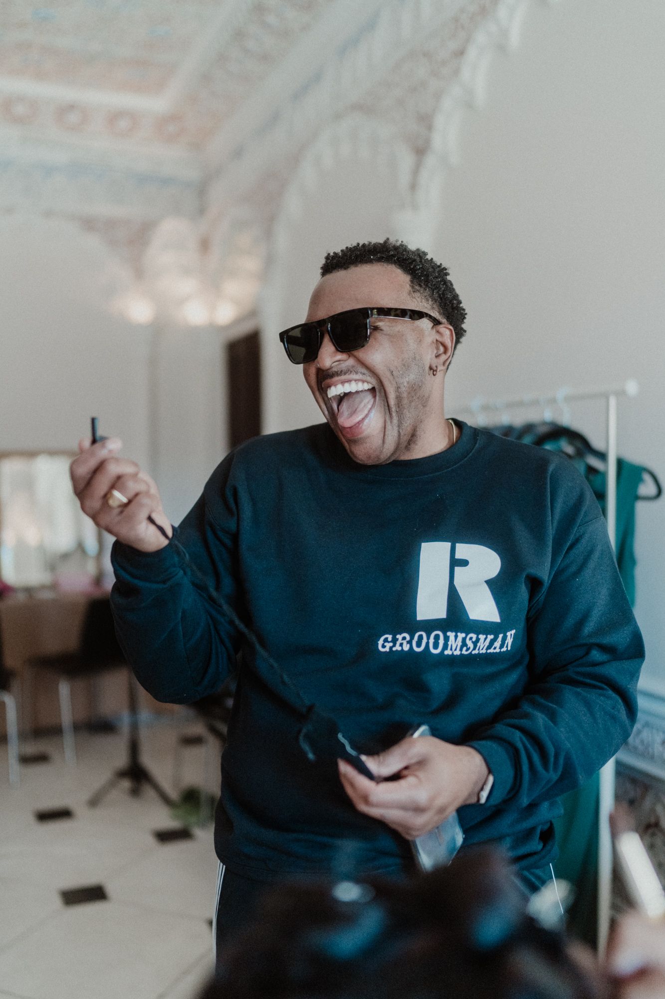 Candid moment of a groom laughing with friends during a relaxed wedding celebration in Portugal