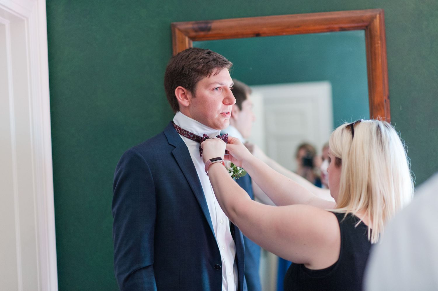 Wedding preparation scene against teal wall with wooden frame.