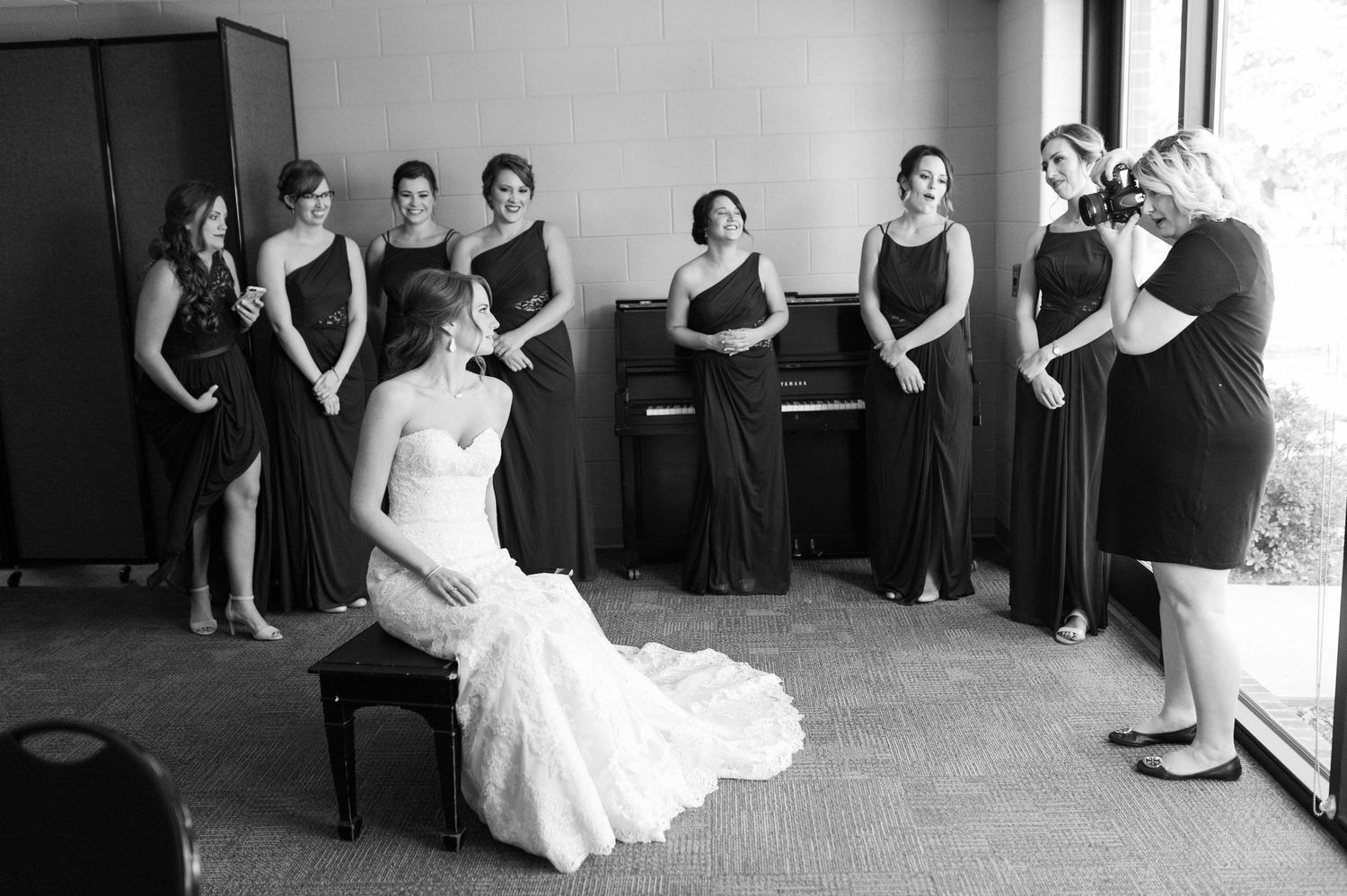 Wedding party members in black dresses seated in a row during formal event.