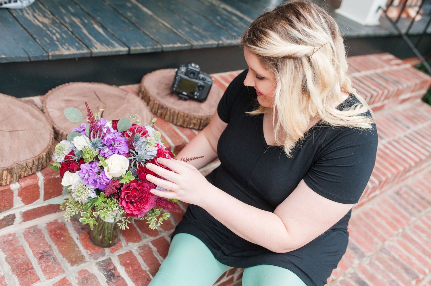 Photographers arranging colorful floral bouquets on brick surface.