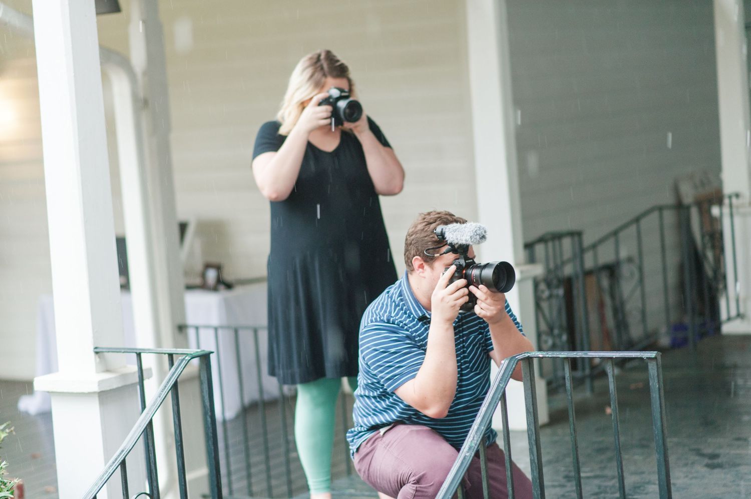 Photographers working at an event in a bright indoor space with white columns.