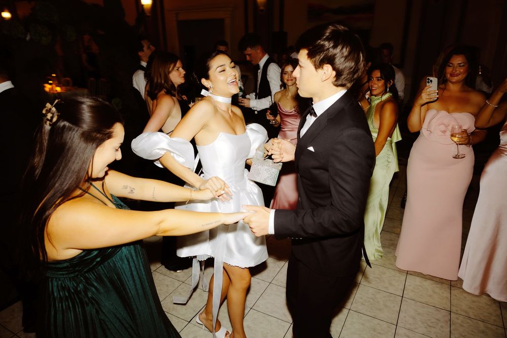 Wedding reception dance floor filled with couples dancing under warm lighting.