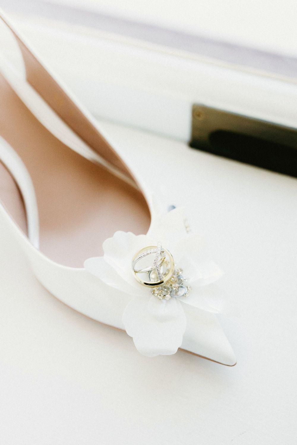 White bridal shoes with rings displayed against light background.
