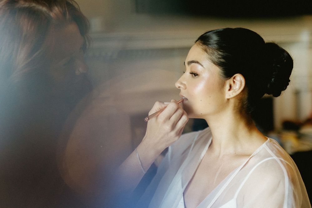 Getting ready moments captured in soft focus with natural window light.