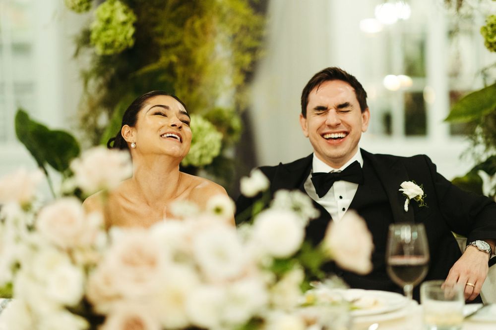 Wedding guests laughing and enjoying themselves during outdoor reception celebrations.