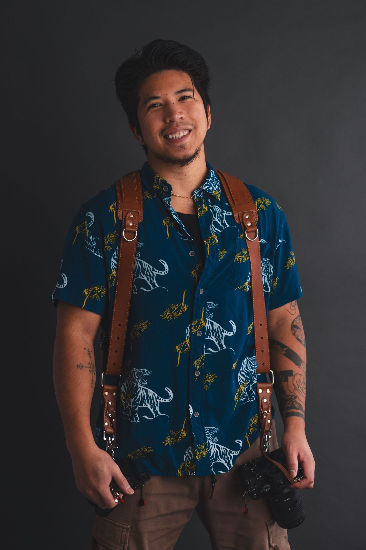 Portrait of photographer wearing dinosaur print shirt and leather camera straps.