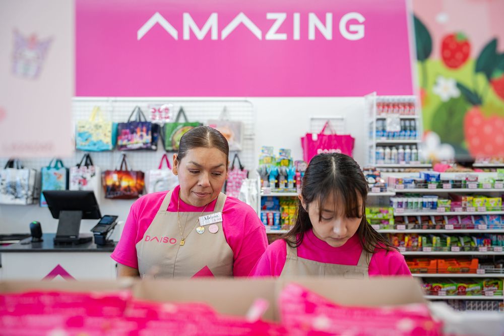 Amazing store employees in pink uniforms assist customers in a brightly lit retail environment.