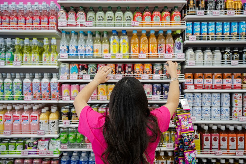 Colorful bottles of beverages and drinks lined up on retail store shelves in a supermarket aisle.