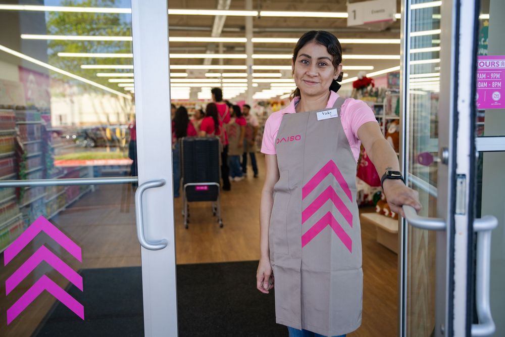 Pink directional arrow signs mounted on glass doors at a retail storefront entrance.