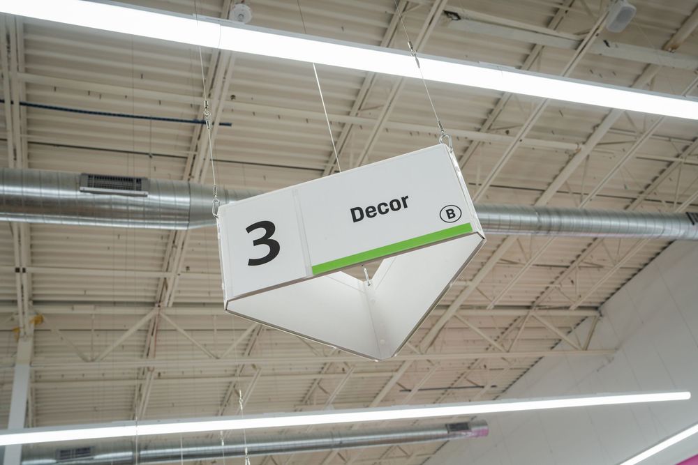 A long fluorescent light fixture mounted on an industrial ceiling with exposed ductwork and wiring.