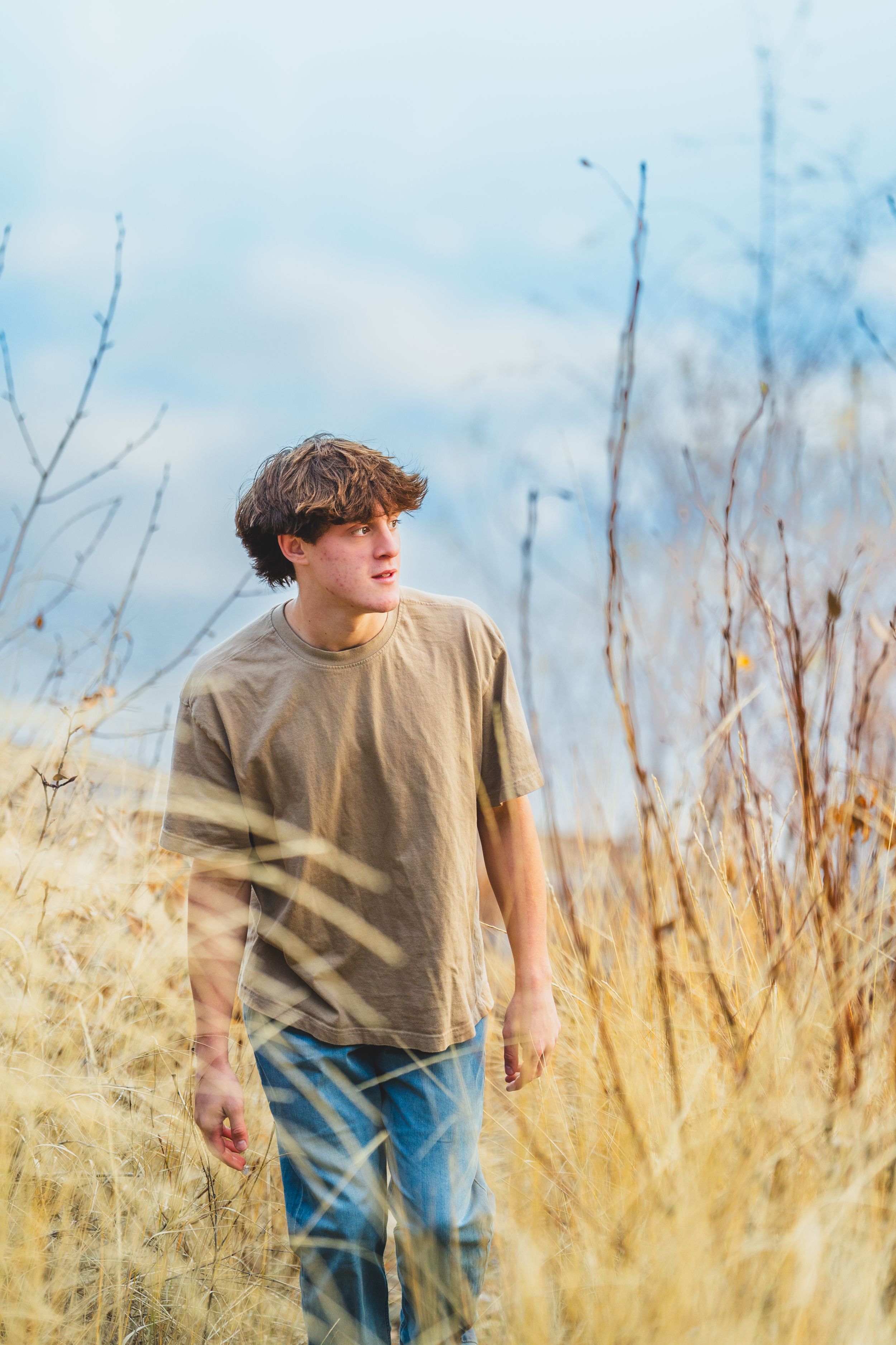Person walking through tall golden wheat field on a bright sunny day.